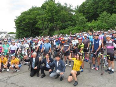 ロードバイクと共に集合した多くの参加者の前に市長や関係者の方が跪いて撮影した写真