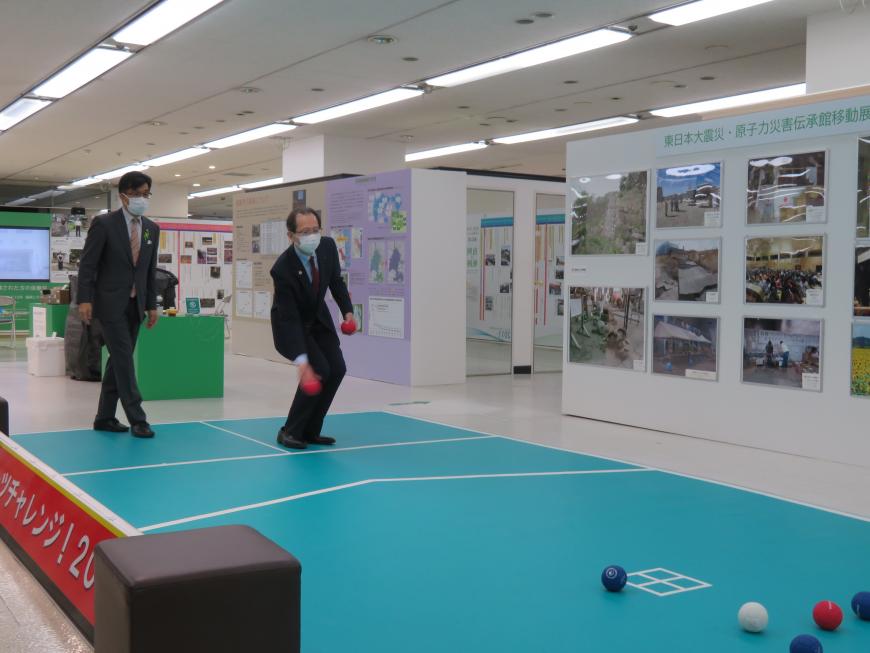 壁に写真が張られている場所で市長と男性がボッチャしている写真