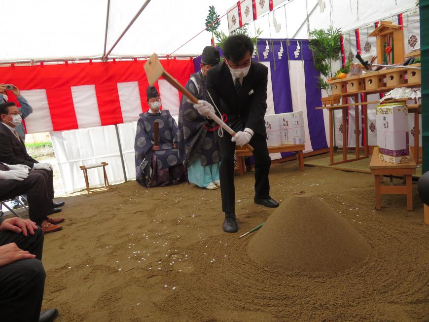 参列者や宮司が見ている中、市長が祭壇の前で鍬入れをしている写真