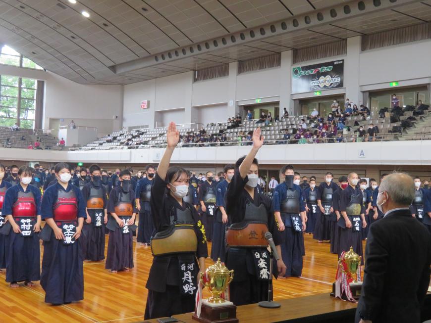 剣道大会の参加選手が整列している前で、男性と女性の選手が選手宣誓をしている写真