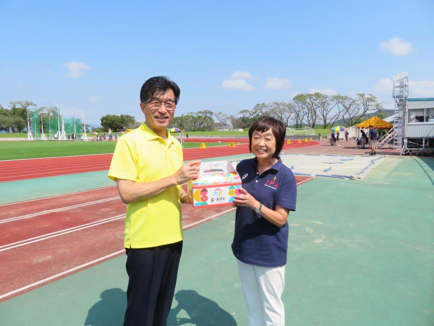 競技場のトラック横で市長が増田明美さんにFBOXを渡している写真