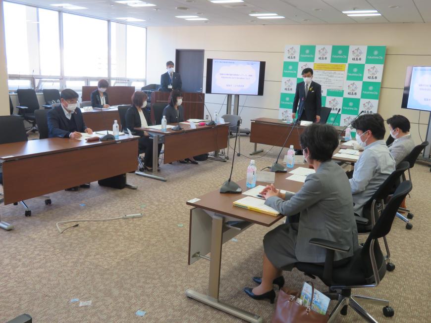 コの字型に配置された長机に座っている参加者の前で、市長が自席で立って話をしている写真