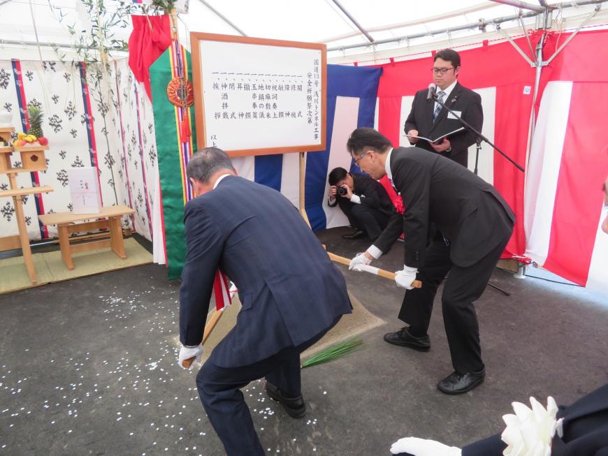 テント内で市長と男性が鍬入れをしているところを後方から撮影した写真