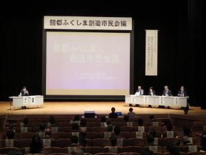 「健都ふくしま創造市民会議」の横断幕があり、壇上で市長と関係者がパネルディスカッションを行っている様子を客席側から見た写真