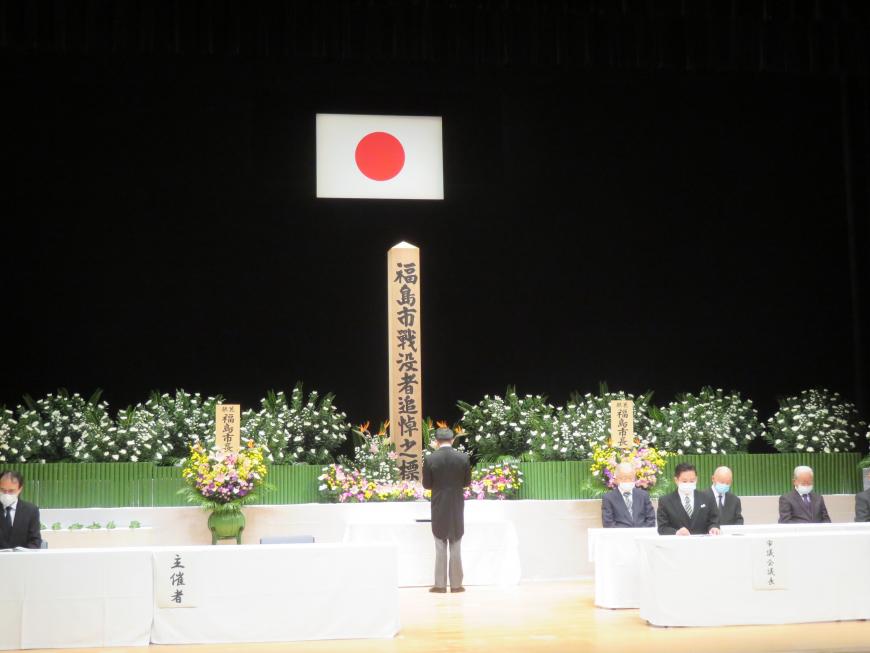 花が飾られた祭壇に向かって、市長が挨拶を述べている写真