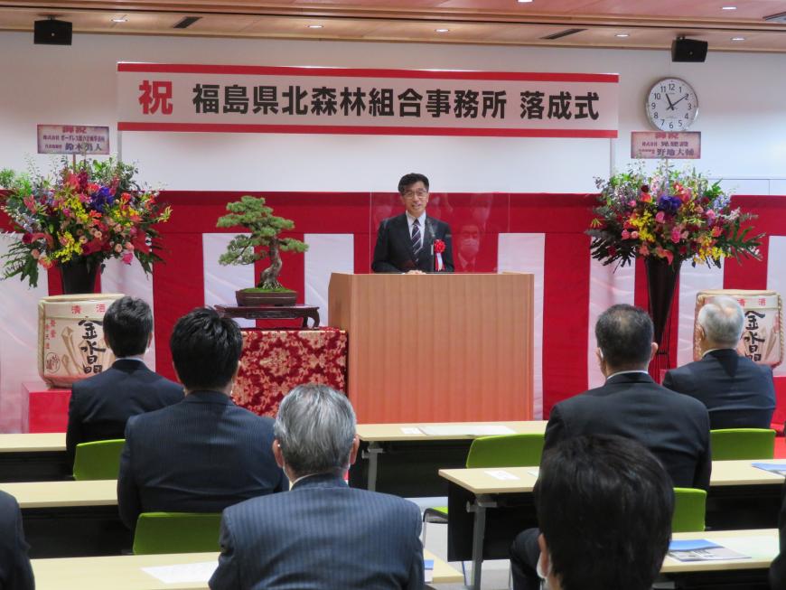 「祝 福島県北森林組合事務所落成式」と書かれた横断幕が設置され、お祝いの花や酒樽が置かれた会場で、座っている参加者の前で市長が演台に立って話をしている写真