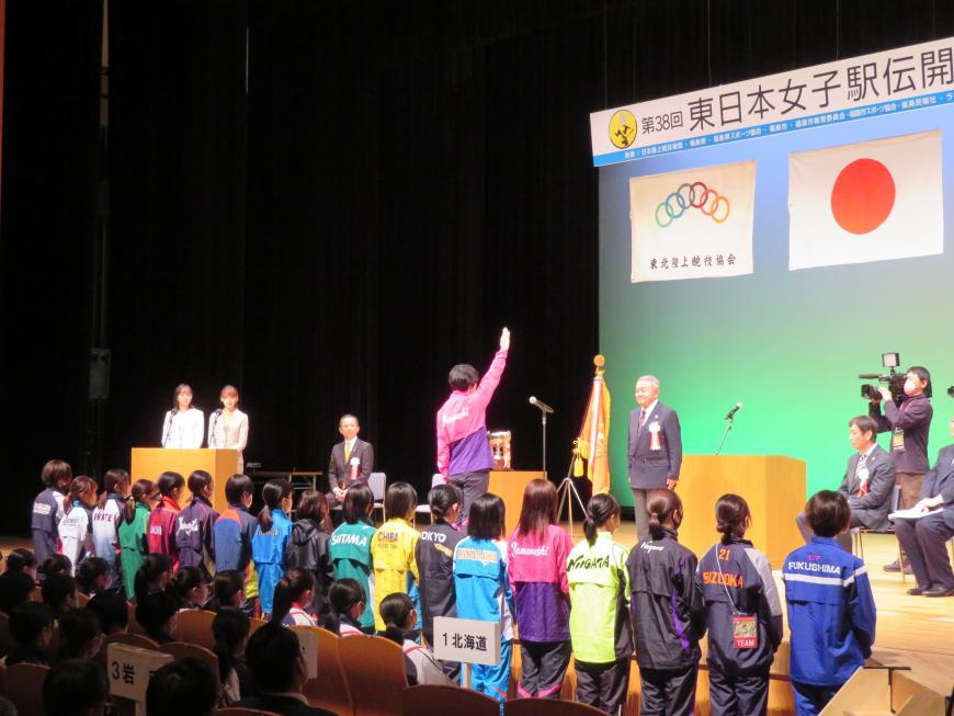 各チームの代表がステージ下に整列し、選手の代表がステージ上に立ち、選手宣誓をしている写真