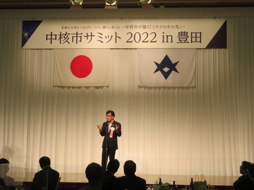 中核市サミットの横断幕が吊るされたステージで市長が参加者の前で話をしている写真