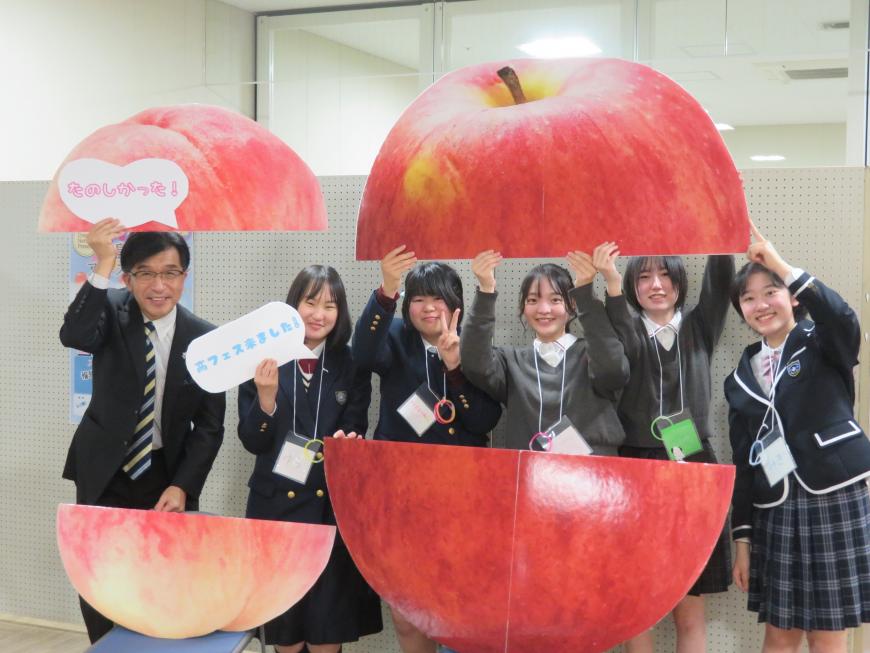 市長と女子高生5名が半分にされた巨大なりんごと桃のオブジェを持っている写真