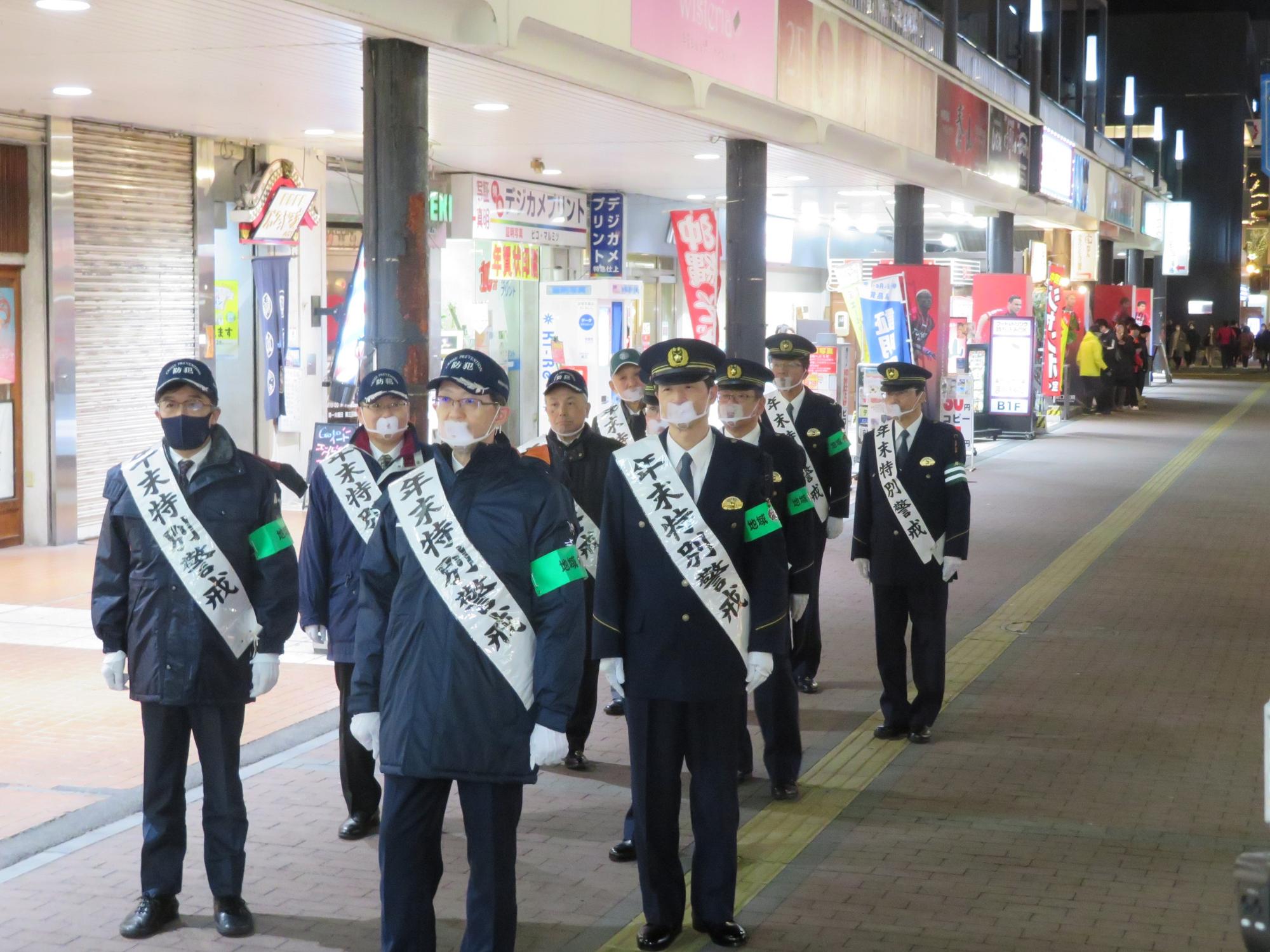 「年末特別警戒」のたすきをかけた市長と関係者らが繁華街を歩いている写真