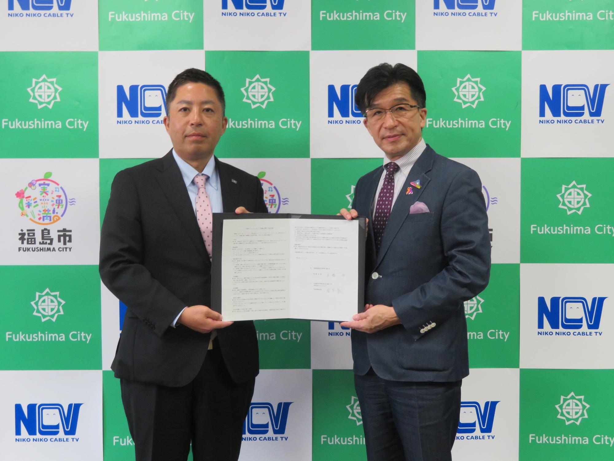 市長と株式会社NCVの関係者が両手で協定書を手に持っている写真