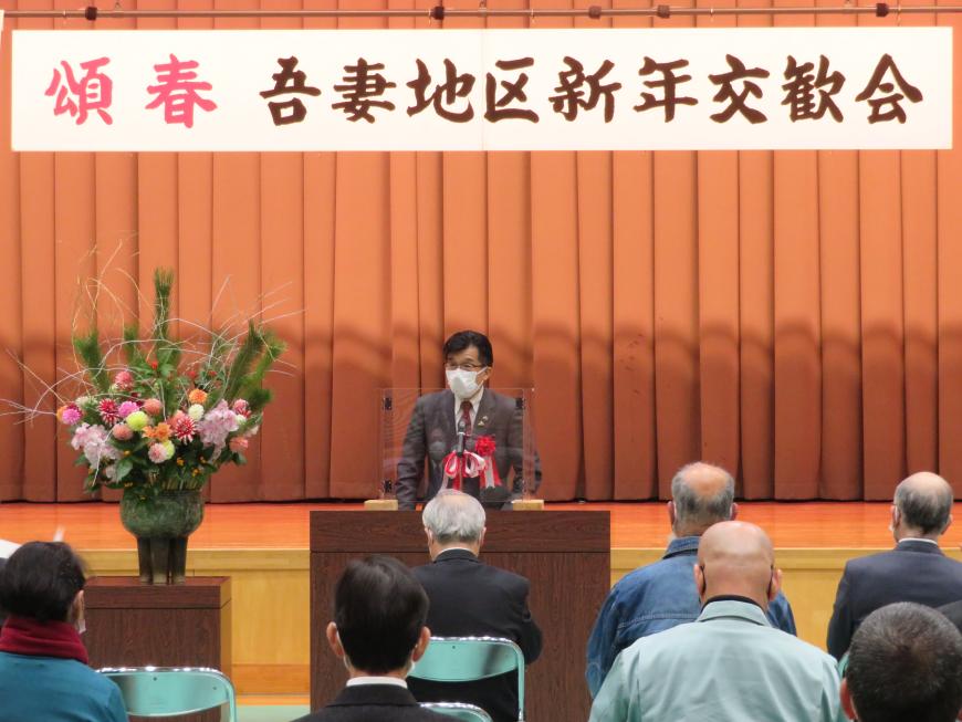 「吾妻地区新年交歓会」と書かれた横断幕がある会場で、座っている参加者の前で、市長が演台に立って話をしている写真