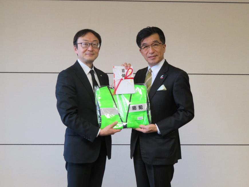 市長と男性で目録と緑色の反射材付きベストを持っている写真
