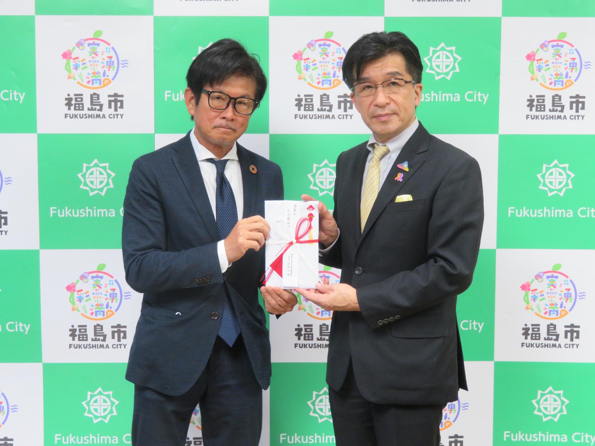 市長と福島県北再生資源協業組合の関係者の男性が、両側から目録の封筒を持っている写真