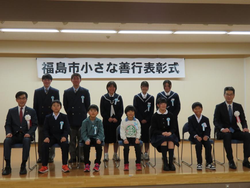 「福島市小さな善行表彰式」の横断幕がある会場で市長と職員の間に胸章をつけた児童が5名前列に座り、後列に5名の生徒が立っている写真