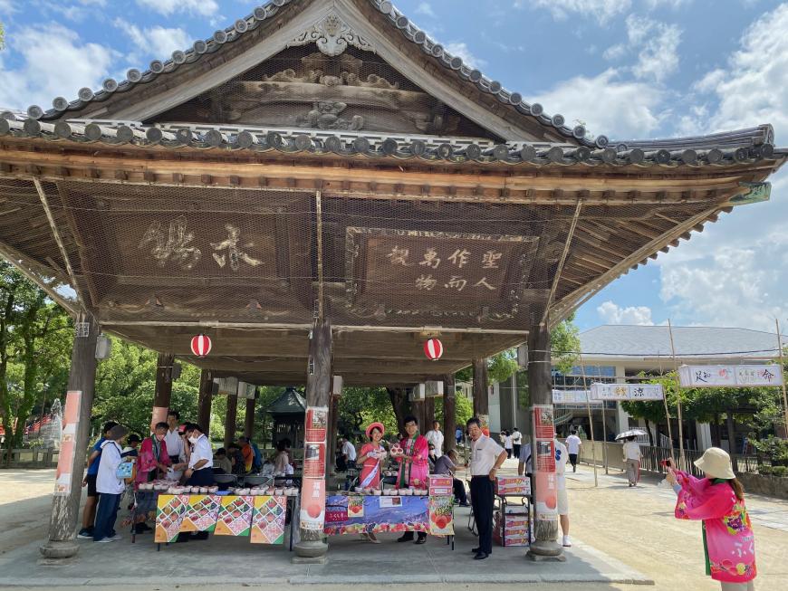 境内の建物で法被を着た市長をミスピーチガールが桃を手にしている写真