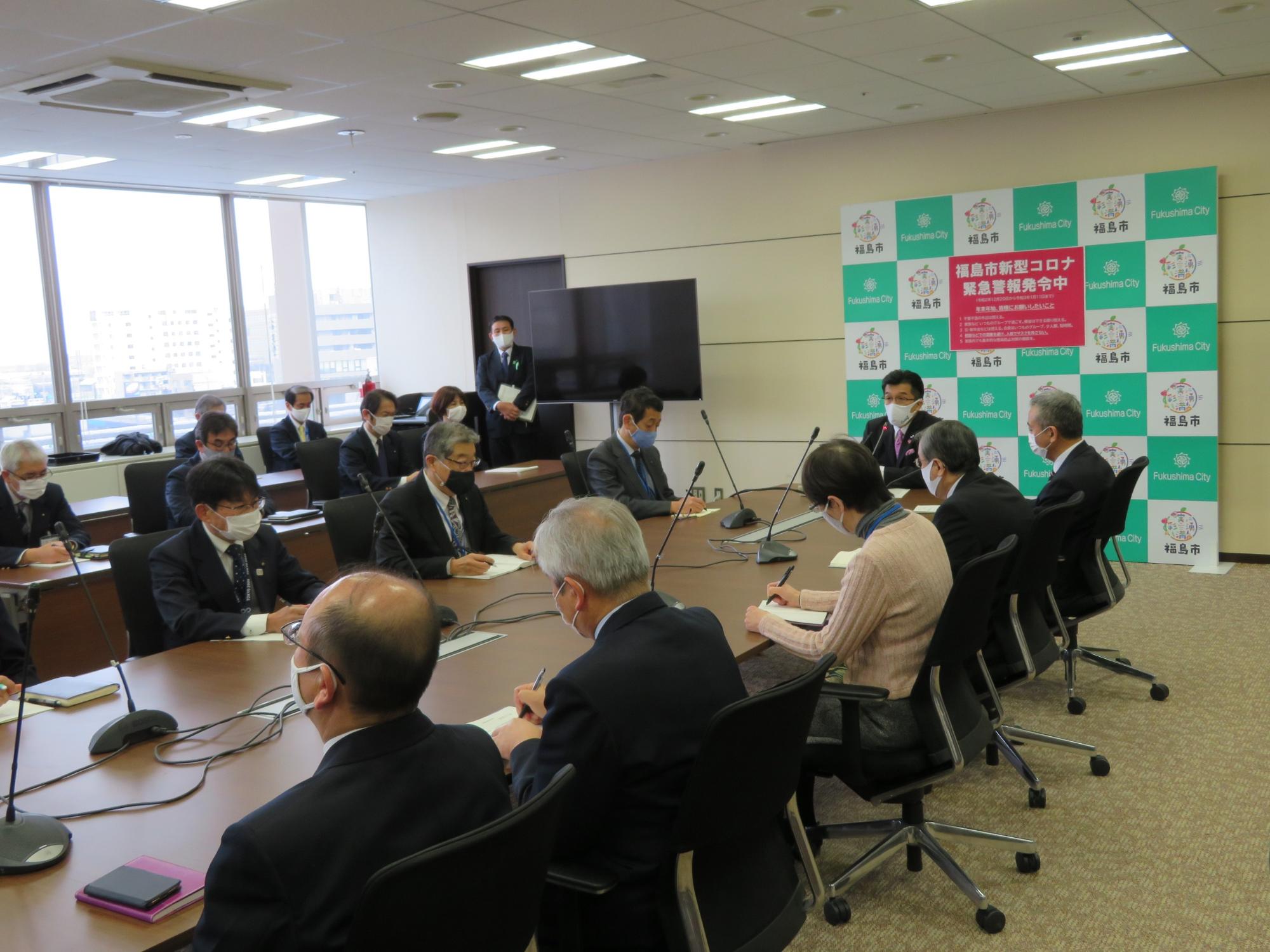 庁議室の一室で、机を囲み、新年市長訓示を参加する職員へ話をする様子の写真