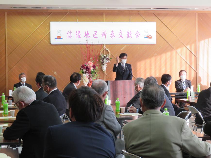 信陵地区新年交歓会と書かれた横断幕がある会場で、参加者が座っている前で、市長が演台に立って話をしている写真