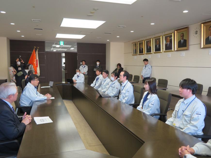 執務室内で市長の前に座った8名の職員に対して話をしている写真