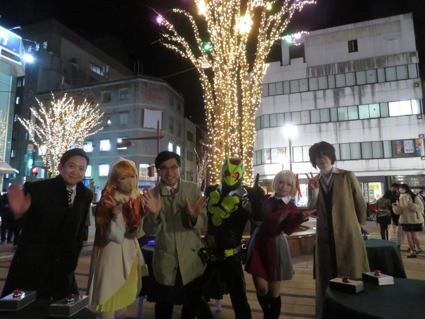 イルミネーションされた街中で、市長とコスプレした4名が並んで撮影した写真