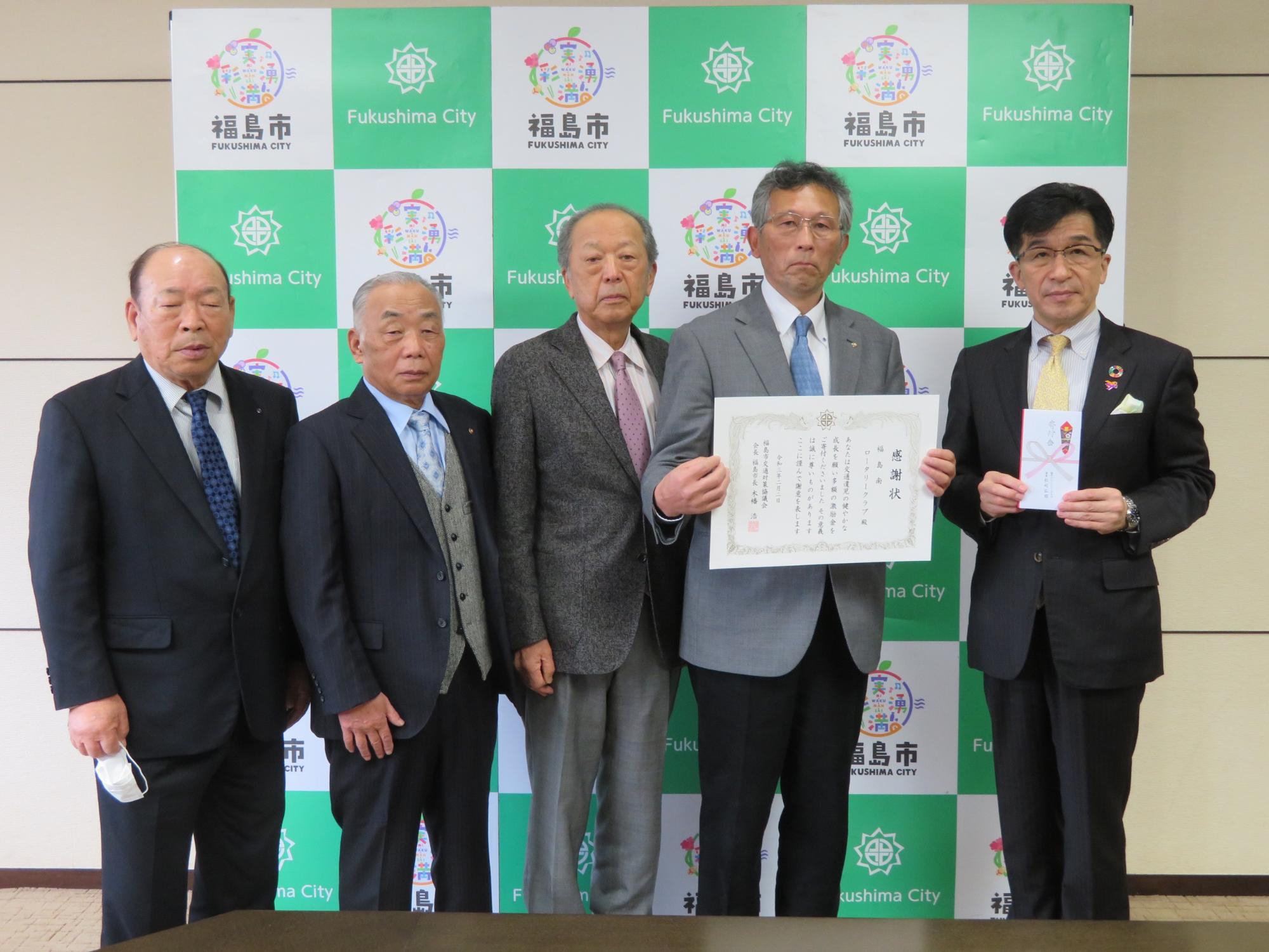 福島市のバックパネル前で、福島南ロータリークラブの関係者4名と市長が目録を手に持ち並んでいる写真