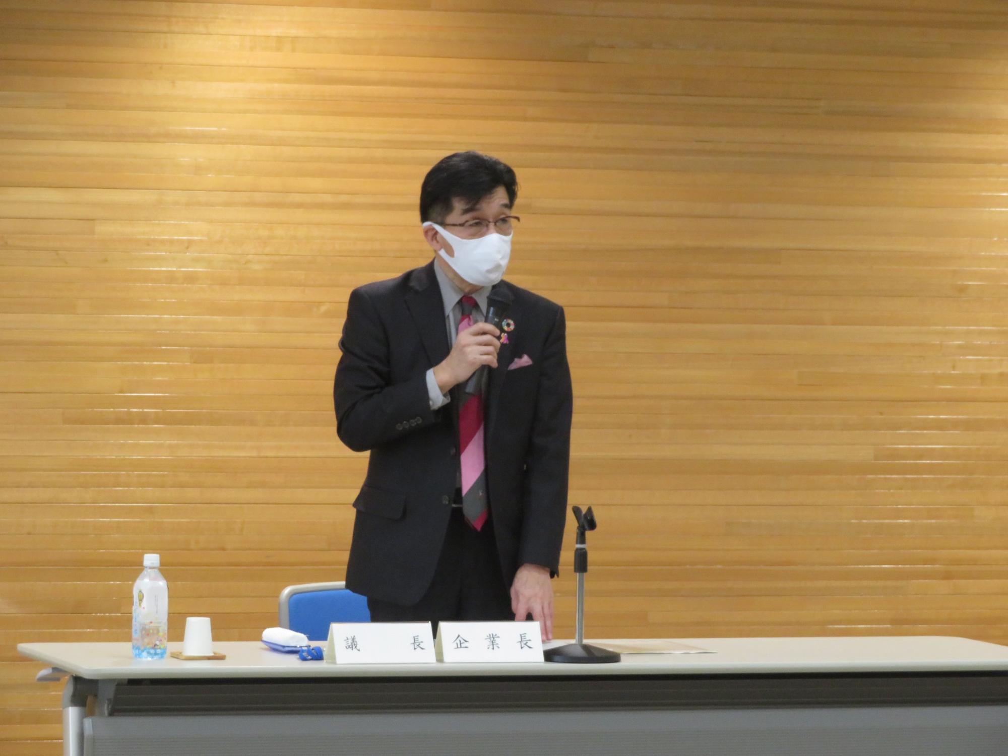 席を立ち、マイクを手に持ち話をする市長の写真