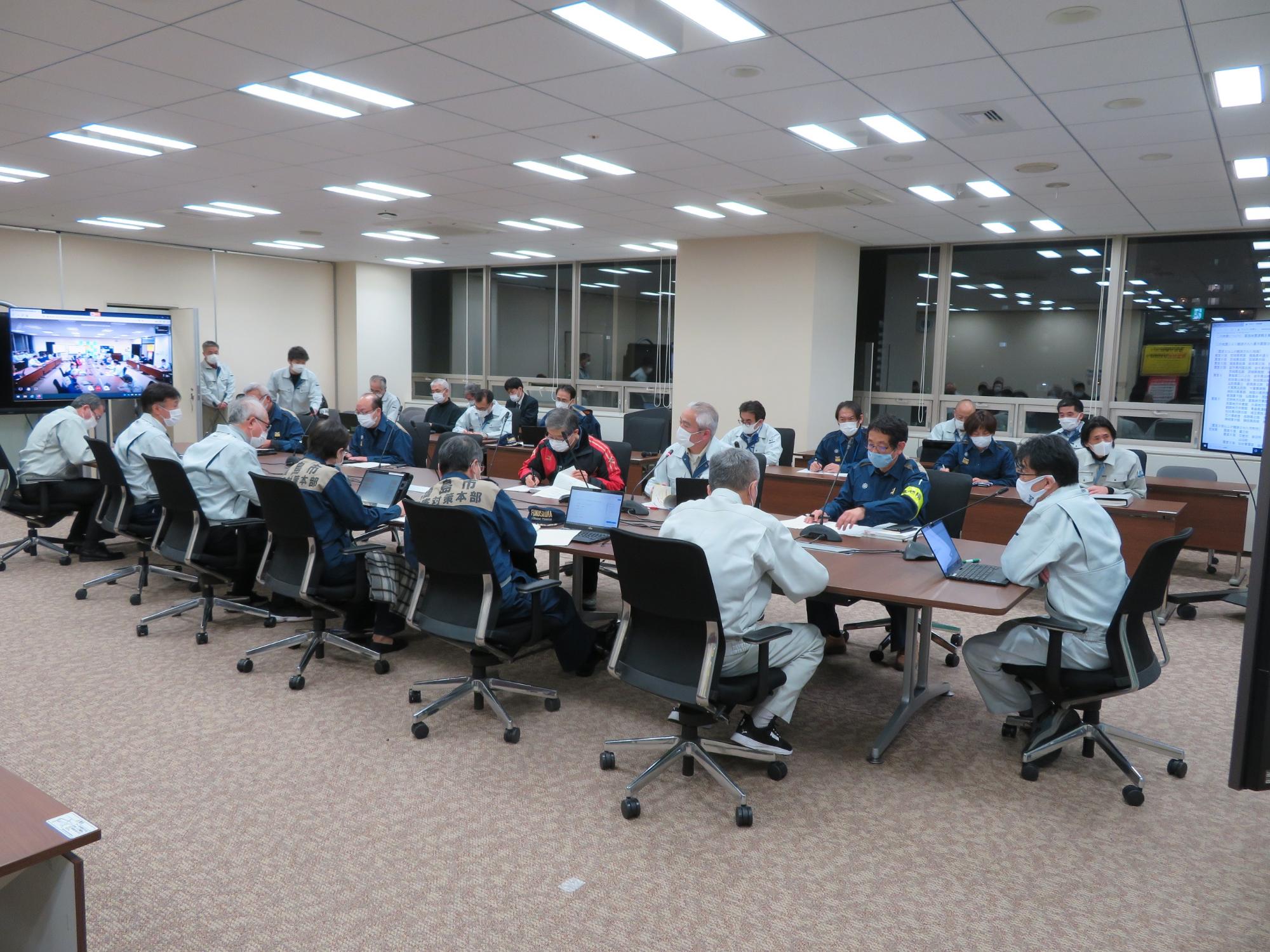 災害対策本部の関係者と市長が庁議室で席に座り、会議を行っている写真
