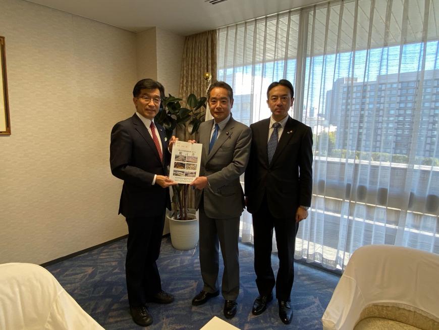 執務室内の窓側で市長と男性で要望書を持ち、隣に男性が1名立っている写真