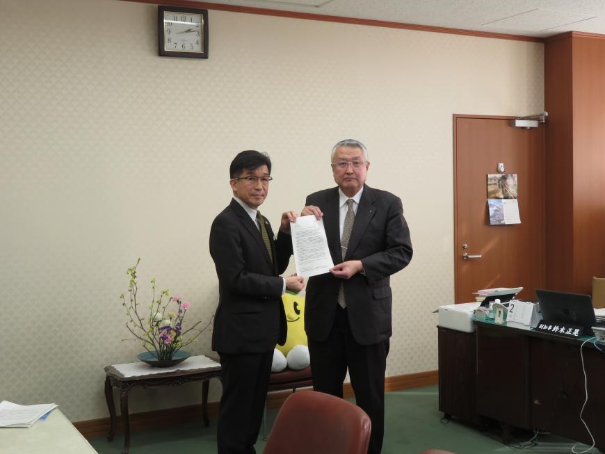 執務室内で市長と男性で要望書を持っている写真