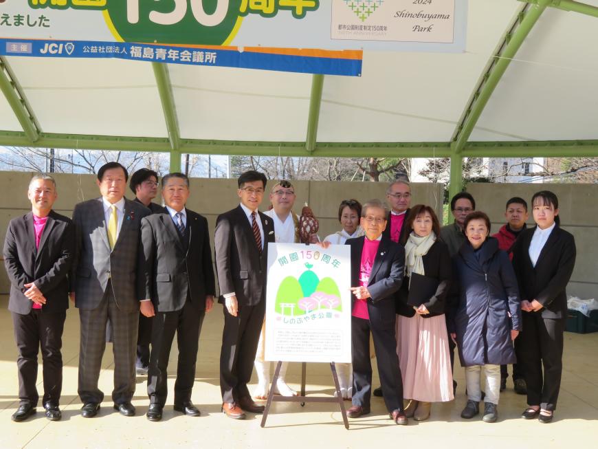 ロゴマークが書かれたボードを中心に市長の他、山伏姿の男性、関係者の方が約15名ほどが並んでいる集合写真