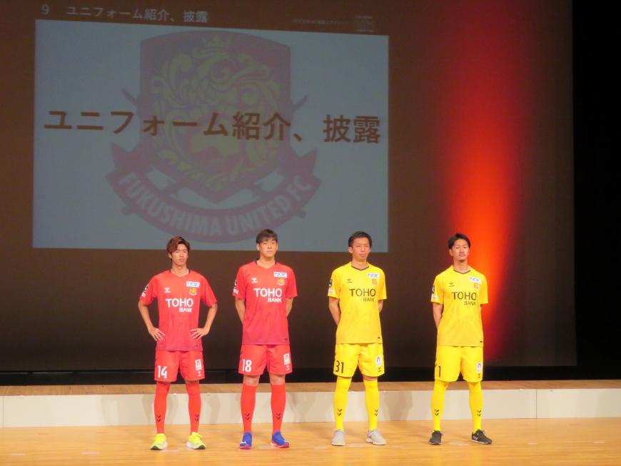 ステージ上に赤色と黄色のユニフォームを着た選手が2名ずつ立っている写真