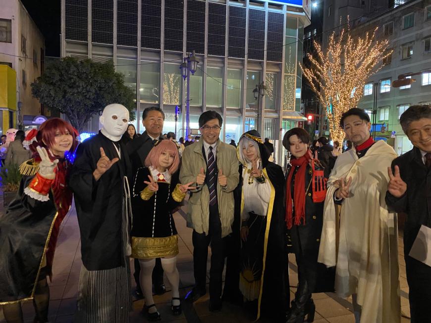 イルミネーションされた夜の街で市長とコスプレした人たちが集合して撮影した写真
