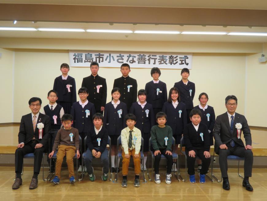 「福島市小さな善行式」のボードがある会場で、最前列に市長と男性の間に5名が座り、2列目に6名、3列目に5名がひな壇状に並んでいる写真
