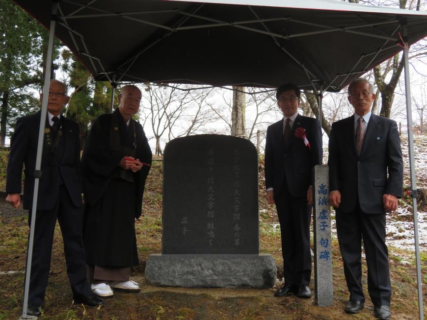 テント内で市長、住職を含む4名が石碑の脇に2名ずつに分かれて立っている写真