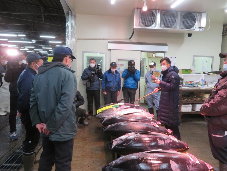 水揚げされた魚の前で、市長が市場関係者の方に話をしている写真
