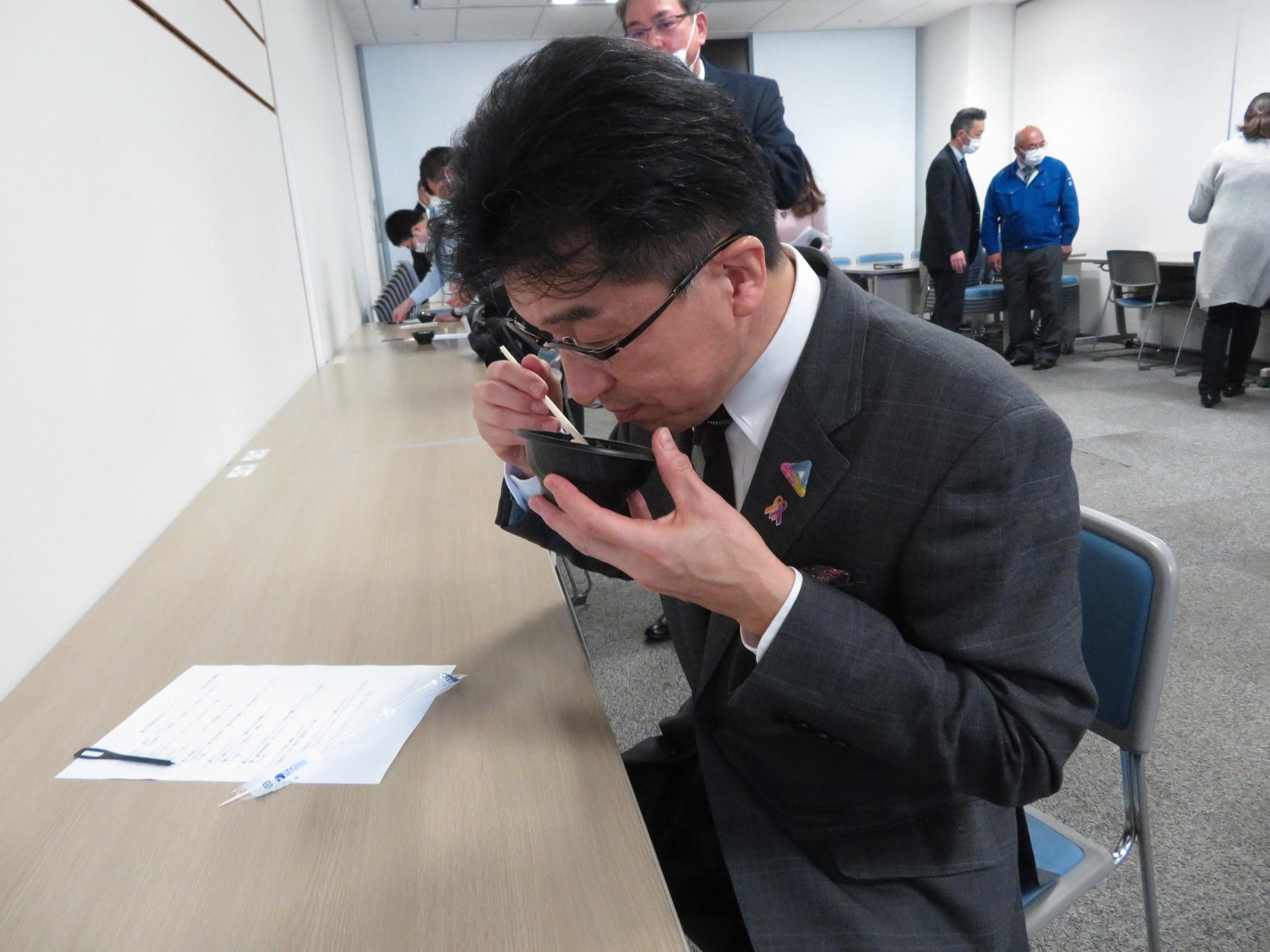 市長がアンケート用紙を机に置いて桃ごはんの試食をしている写真