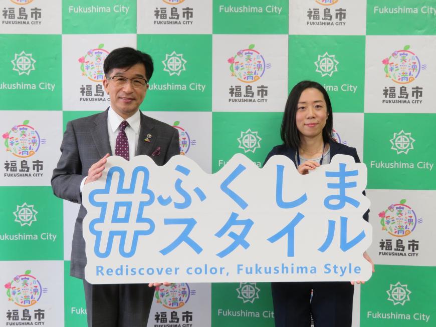 バックパネルの前で、市長と女性で「ふくしまスタイル」と書かれたボードを持っている写真