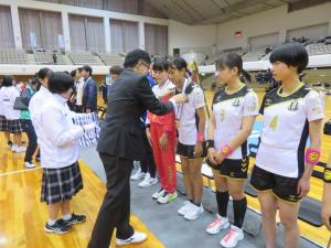 市長が横一列に並んでいるユニフォーム姿の女子選手の1人にメダルをかけている写真