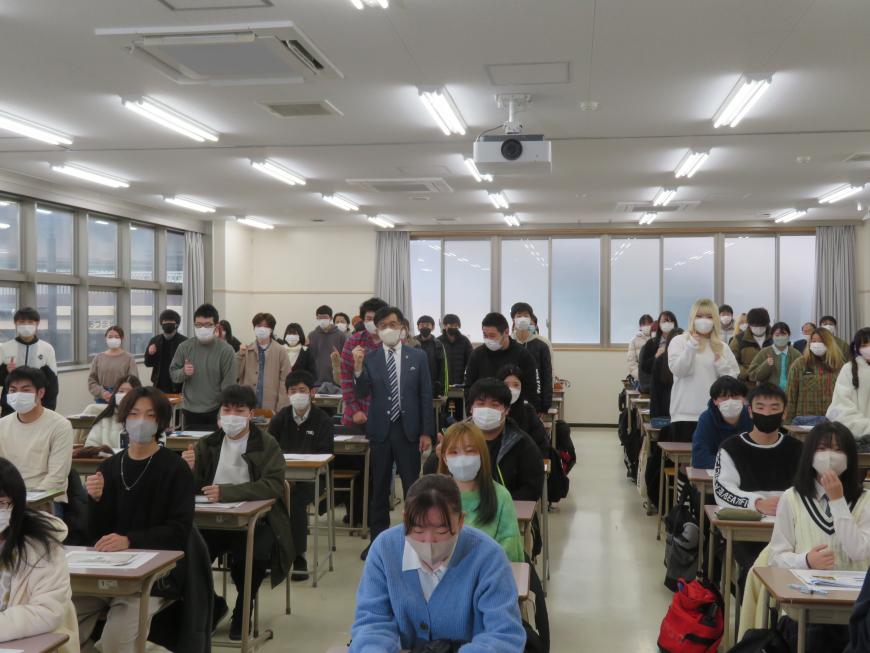 市長が自席で立っている参加者と自席に座っている参加者の机の間を歩いている写真