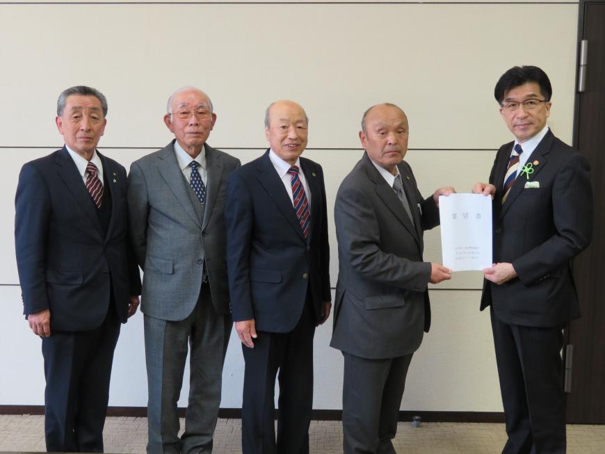 市長と男性が要望書を一緒に持ち、男性の横に3名の関係者の男性が一緒に並んで記念撮影している写真