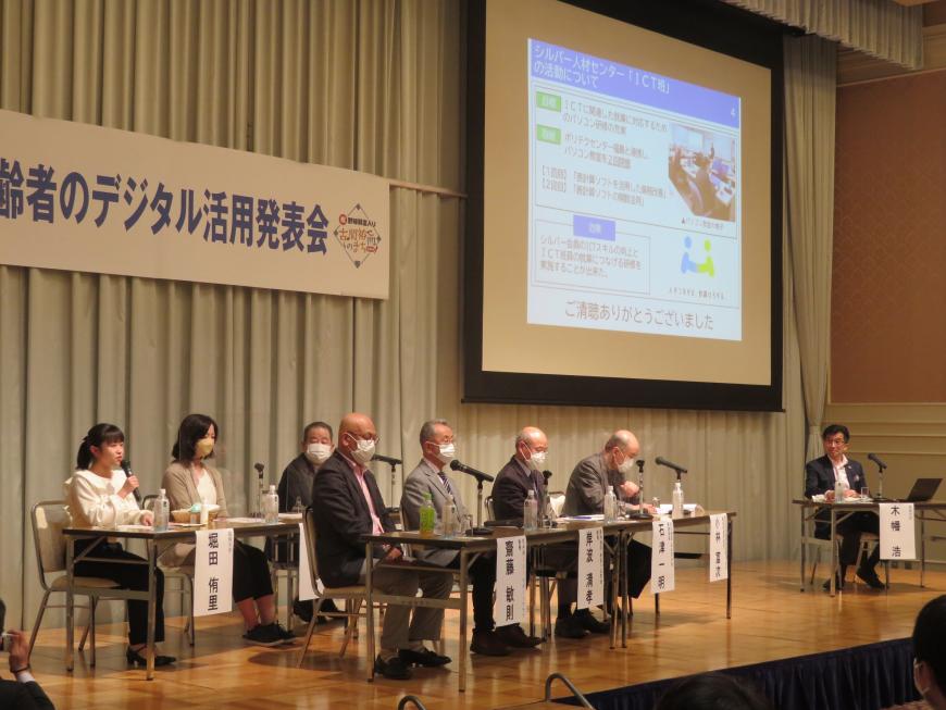 ステージ上に2列に座っている参加者の方々とスクリーンをはさんで座っている市長が画像を見ながら話をしている写真