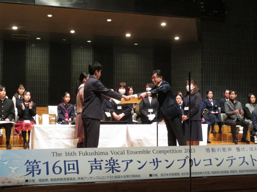 参加者が座っている前で、市長が入賞した生徒に賞状を渡している写真