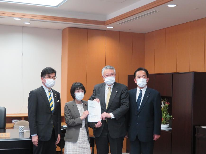 執務室内で女性と男性で要望書を持ち、その横に市長と男性が立っている写真