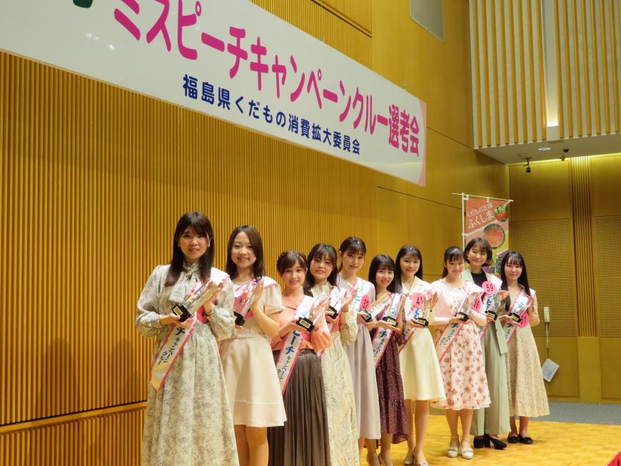 選ばれた10名のミスピーチキャンペーンクルーがそれぞれ襷をかけ、盾を持ち横一列に並んで右側を向いた状態で記念撮影をした写真