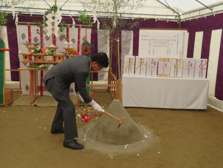 お供え物が置かれている祭壇の前で、市長が鍬入れをしている写真