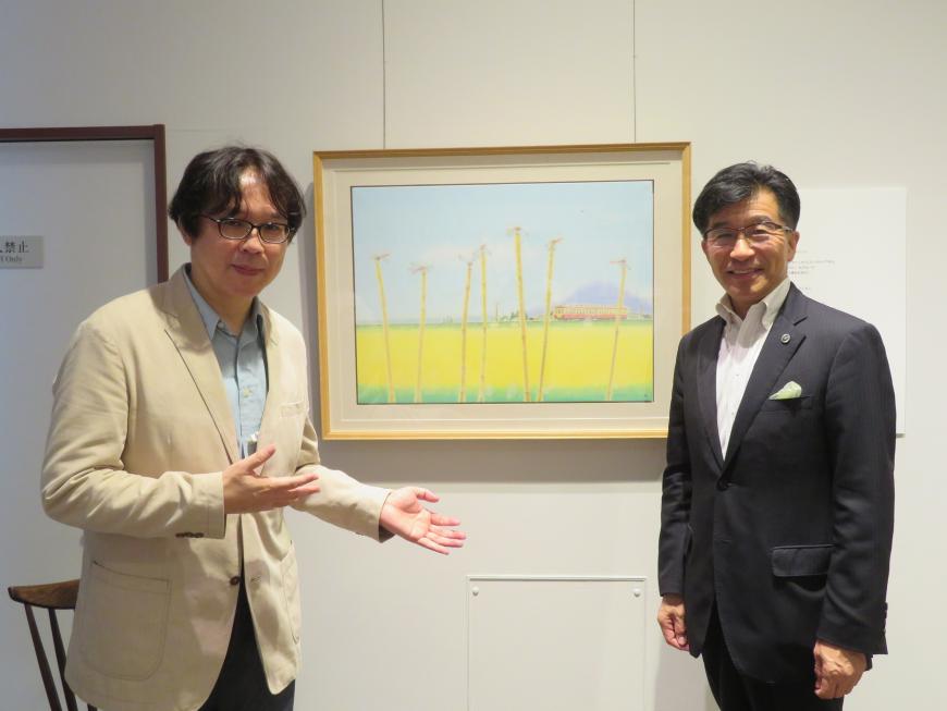 壁に掛けてある絵画の横に市長と男性が立っている写真