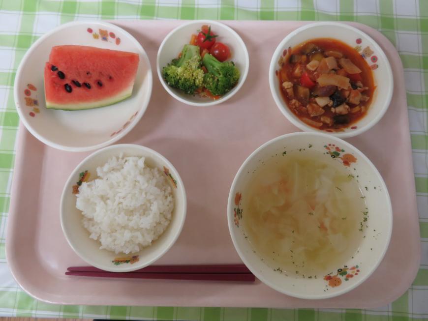 ピンク色のトレーにご飯、スープ、ラタトゥイユ、ブロッコリーとトマトの小皿、スイカが載っている写真