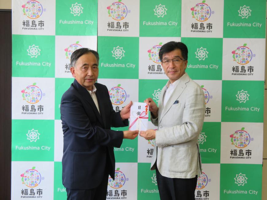 バックパネルの前で、市長と男性で目録を持っている写真