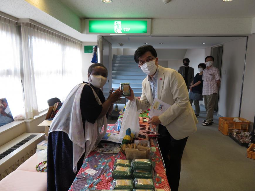 机に置かれた商品の上で、市長と黒人の女性が商品を持っている写真