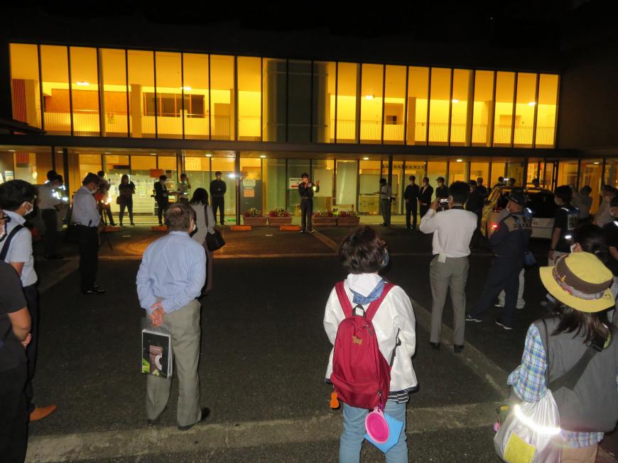 照明がついている建物の外で訓練に参加した人たちが、間隔をとりながら集まっている写真